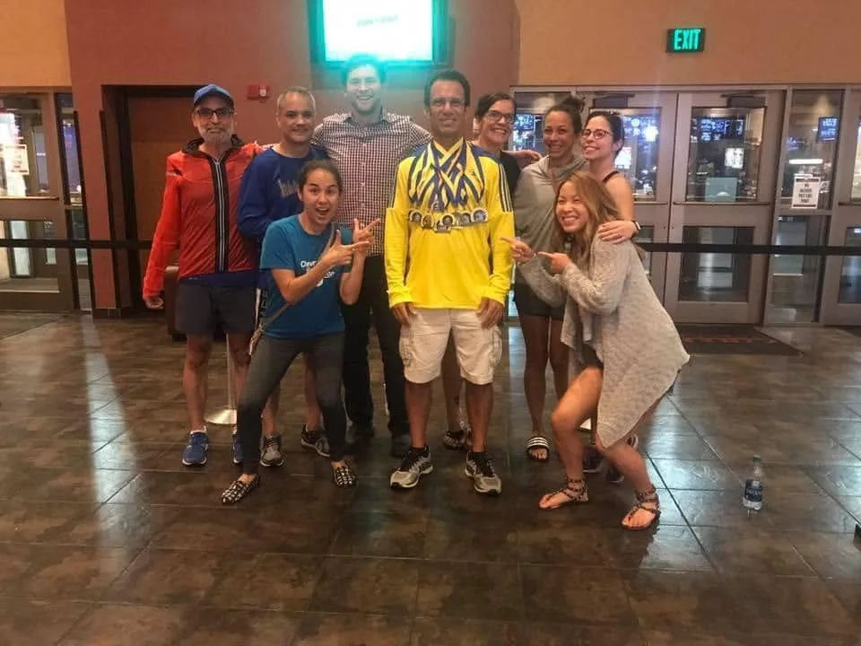 Larry wearing a stack of Boston Marathon medals, surrounded by smiling friends