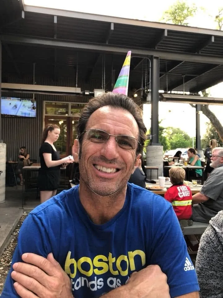 Larry grinning in his Boston shirt and a party hat