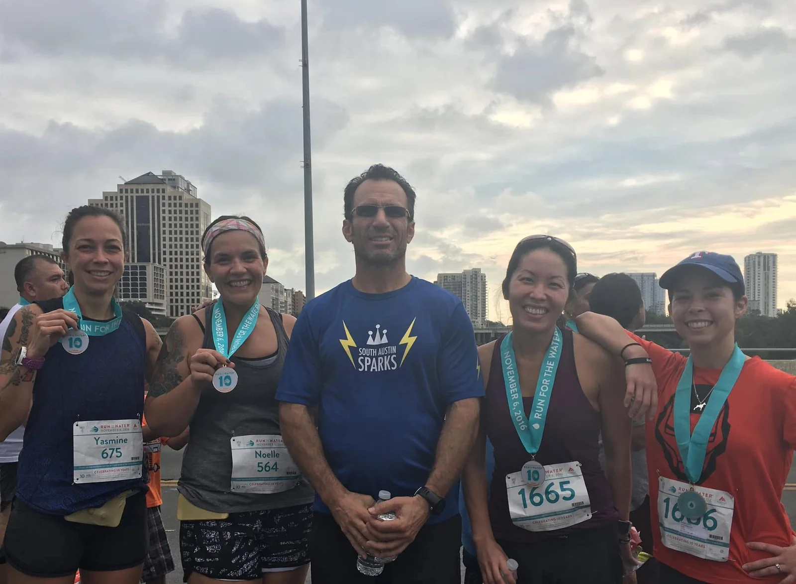 Larry and fellow runners wearing race medals on a bridge